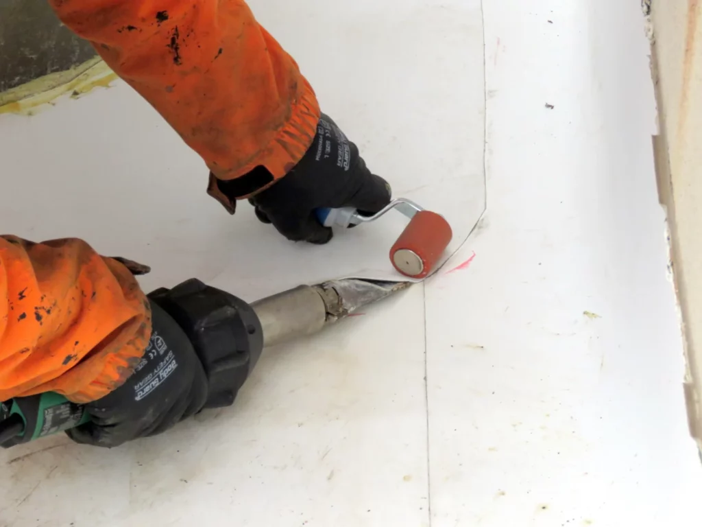 A roofer heat-welding TPO roof flashing during a TPO roof installation. In this case, the TPO roofing cost around $11 per square foot.