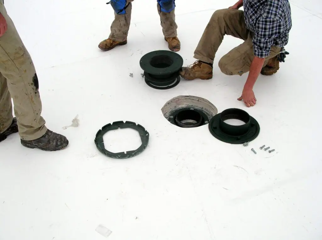 Installing roof drains on a PVC roof.