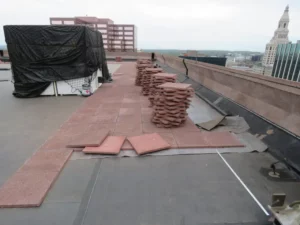 Brick-colored concrete pavers being installed as ballast on an EPDM roof.