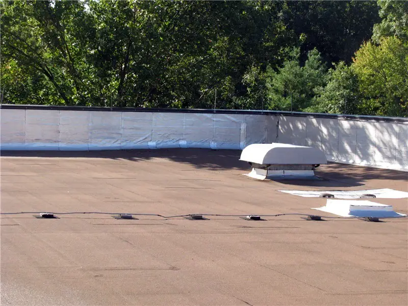 A tan granule-surfaced modified bitumen low-slope roof.