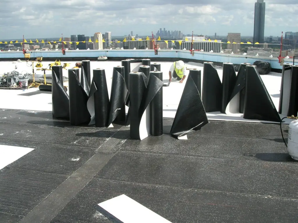 Rolls of modified bitumen roofing standing on end during a roof installation.