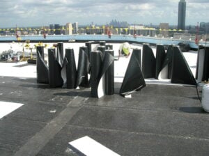 Rolls of modified bitumen cap sheet on a roof before installation over the in-place base sheet.