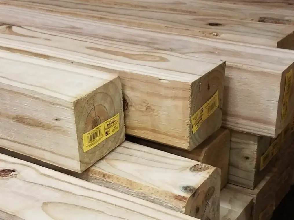 A stack of pressure-treated 4×4 lumber. These posts weigh around 3 and a half pounds per foot.