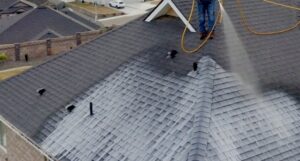 A applicator spraying an asphalt shingle rejuvenation product on a roof.