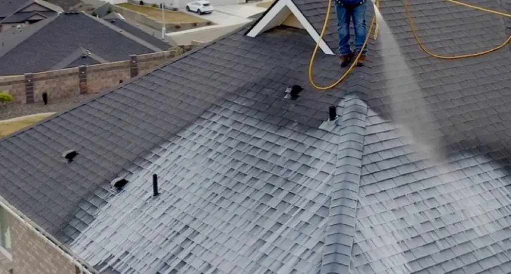A applicator spraying an asphalt shingle roof rejuvenation product on a roof.