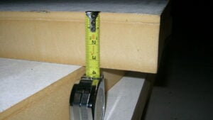 A tape measure showing the thickness of a piece of composite polyisocyanurate insulation board with total r-value R-19.5.