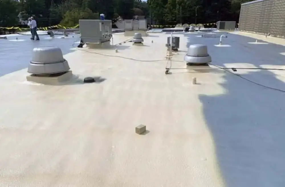 A spray polyurethane foam roof while the silicone coating (gray) is being applied.