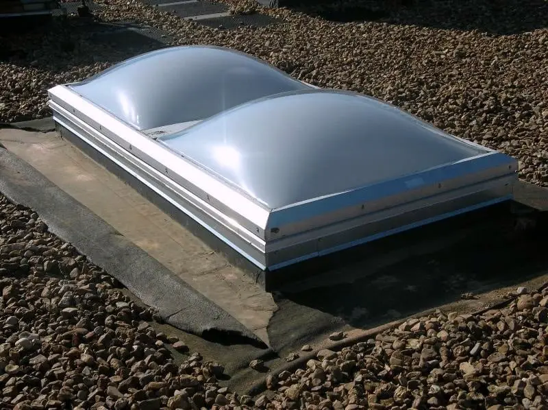 A smoke vent on a ballasted EPDM roof where you can see filter fabric between the ballast stone and the roof membrane.