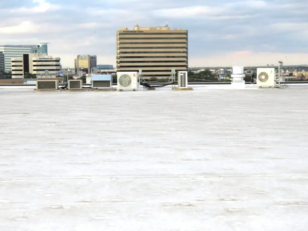 A commercial TPO membrane low-slope roof with other buildings in the background.