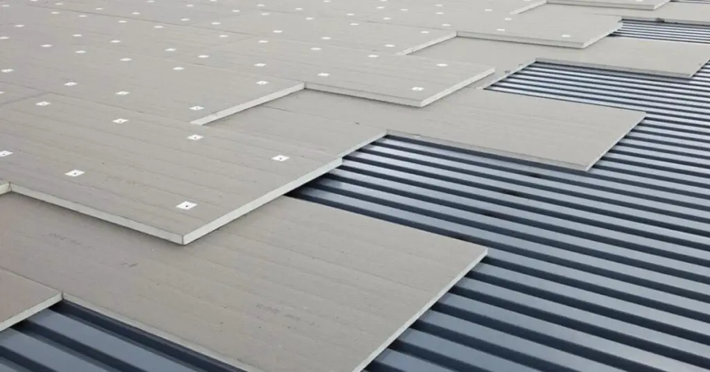 Installing polyiso insulation over a steel roof deck during a TPO roof installation.